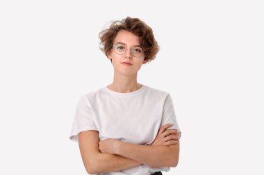 Beyaz gömlekli ve gözlüklü, el ele tutuşan kameraya bakan kendinden emin genç bir kadın.