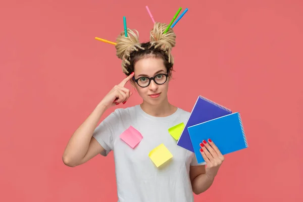 Estudante com notas pegajosas em uma camisa e marcadores em dreads segurando notebook e apontando para a cabeça — Fotografia de Stock