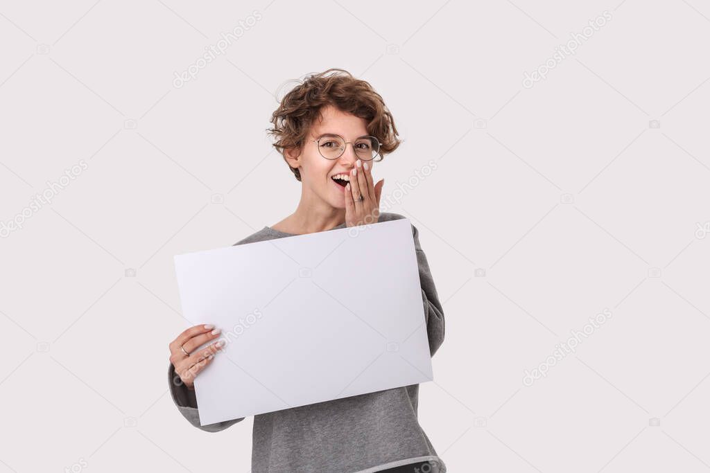 Smiling young woman with eyeglass holding empty blank paper board with copy space for text.