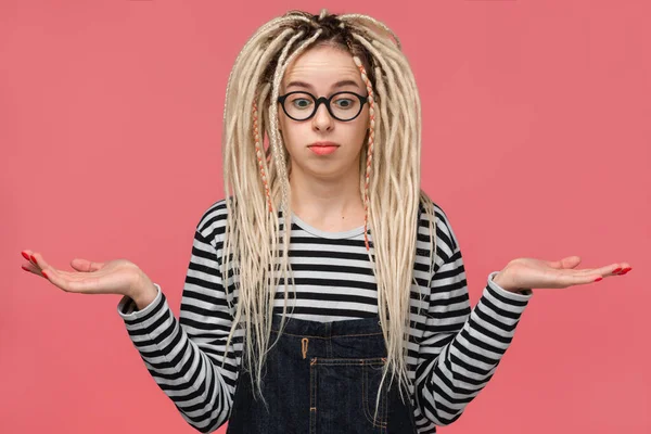 Hesitant Young Girl Long Dreads Standing Pink Background Shrugs Shoulders — ストック写真