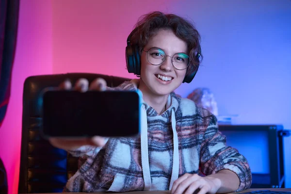Ładna Młoda Kobieta Okularach Bezprzewodowych Słuchawkach Pokazuje Ekran Smartfona Przed — Zdjęcie stockowe