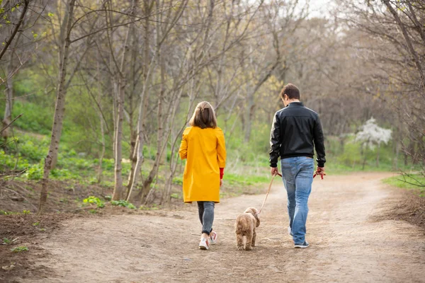 Genç bir çift ormanda bir köpekle yürüyor. Sarı ceketli genç bir kadın kameraya bakıyor. Mutlu aile