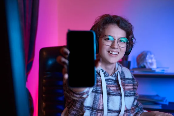 Ładna Młoda Kobieta Okularach Bezprzewodowych Słuchawkach Pokazuje Ekran Smartfona Przed — Zdjęcie stockowe