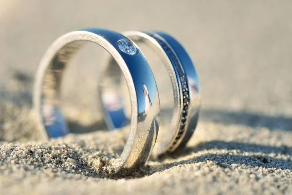 Anéis de casamento na areia com reflexão — Fotografia de Stock