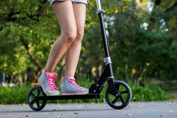 Genç sporcu kadın parkta asfalt yolda bir tekme scooter üzerinde — Stok fotoğraf