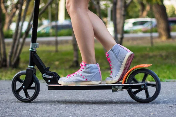 Kadın atlet genç güneşli yaz gününde parkta bir tekme scooter üzerinde biniyor