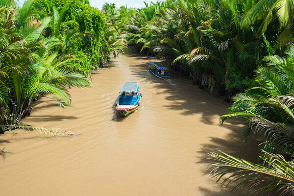 Empty tourist boat is floating very quickly down a river with mu