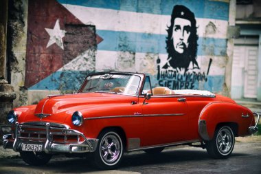 Havana'da kırmızı retro araba ile portre Che Guevara'nın duvarının yakınında