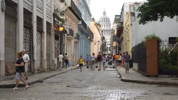 Ludzie, turystów, mieszkańców idą na centralnej wąskiej ulicy wiodących do głównego placu z celownikiem Capitol w Hawanie — Wideo stockowe