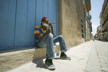 Yaşlı adam sakallı ve örgü içinde kırmızı bandana oturur basamakta n