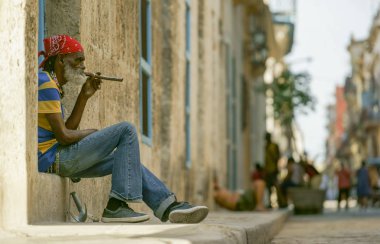 Yaşlı adam dilenci sakal ve örgü içinde kırmızı bandana ile oturur