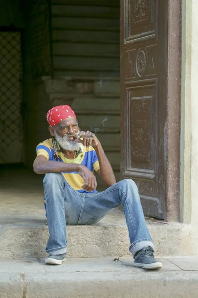 Starší afro muž s plnovousem a copánky v červeném šátkem sedí na s — Stock fotografie