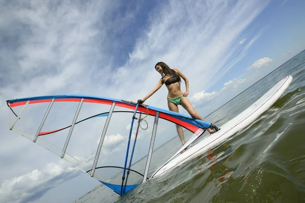 Jeune belle fille chevauche sur le bureau de surf dans la mer — Photo