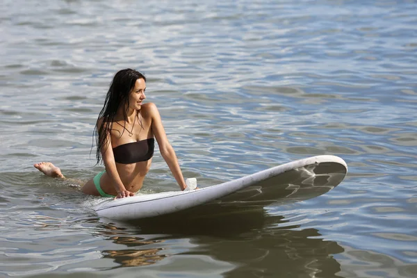 Молодая красивая девушка плавает на серфинг стол в море — стоковое фото
