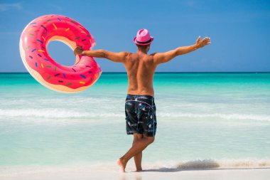 Büyük şişme t ile duran pembe şapkalı mutlu yakışıklı adam