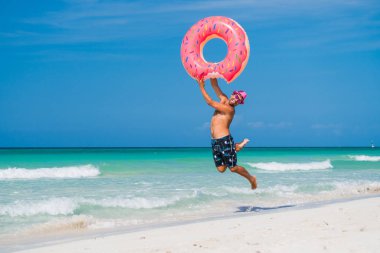 Büyük bir inflatab ile mutlu yakışıklı gülümseyen adam pembe şapkalı atlar