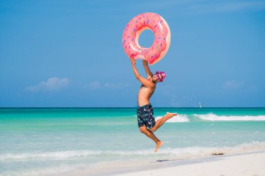 Pembe şapkalı mutlu yakışıklı adam büyük şişme küveti atıyor