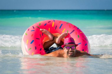 Mutlu yakışıklı adam pembe şapkalı t büyük şişme tüp üzerinde yüzüyor