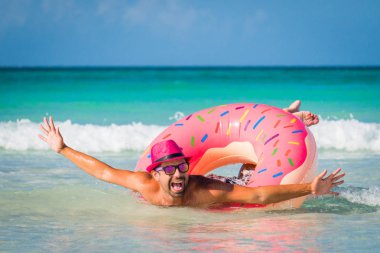 Mutlu pembe şapkalı adam komik gülümseyen yakışıklı üzerinde büyük inflat yüzüyor