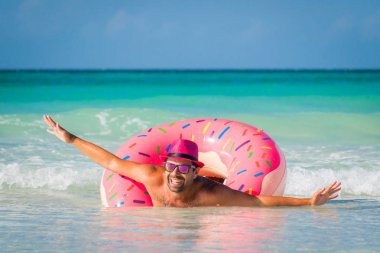 Mutlu komik yakışıklı gülümseyen adam pembe şapkalı büyük üzerinde yüzüyor 