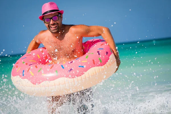 Pembe şapkalı mutlu yakışıklı gülümseyen adam büyük inflatab ile eğlenir
