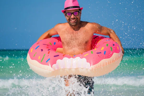 Bonito homem sorridente feliz em chapéu rosa corre com um grande inflatabl Imagens Royalty-Free