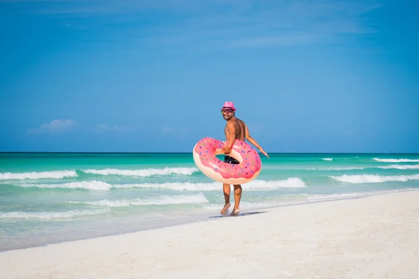Homem bonito feliz no chapéu cor-de-rosa anda com um anel inflável grande Fotografias De Stock Royalty-Free