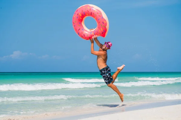 Homem bonito feliz no chapéu cor-de-rosa está saltando com tu inflável grande Imagem De Stock