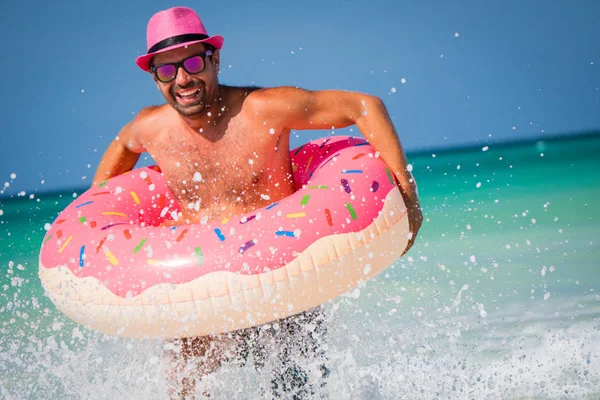 Feliz bonito sorrindo homem em chapéu rosa se diverte com grande inflatab Fotografia De Stock