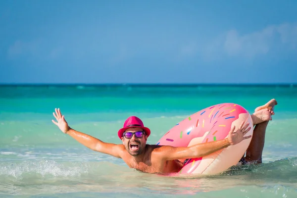 Glad snygg rolig leende man i rosa hatt simning på stora Stockbild