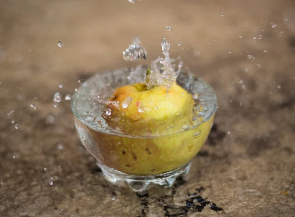 Água corrente e maçã caindo em um copo — Fotografia de Stock