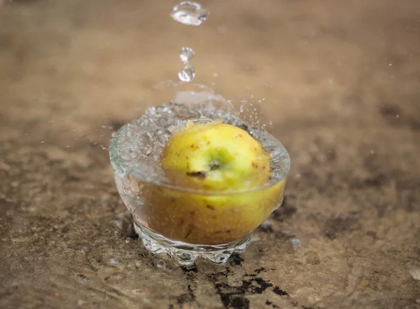 Вода течет и яблоко падает в стакан — стоковое фото
