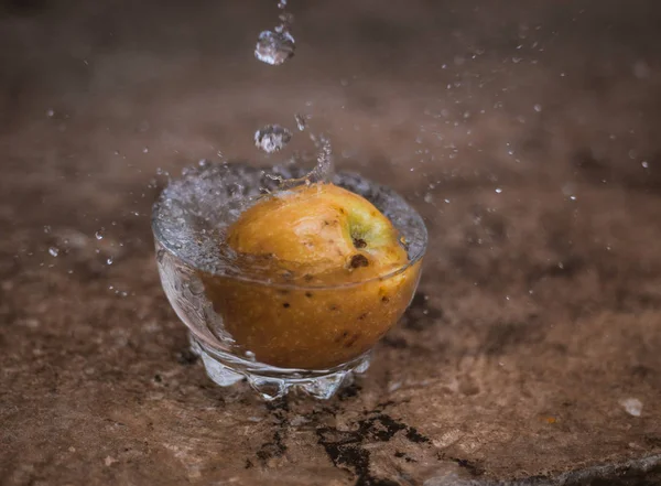 Água corrente e maçã caindo em um copo — Fotografia de Stock