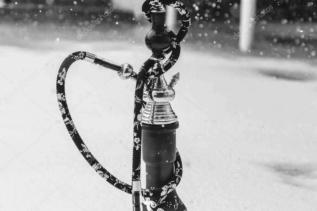 Big hookah for tobacco made of metal, glass and ceramics. Snowing. Snow background. White
