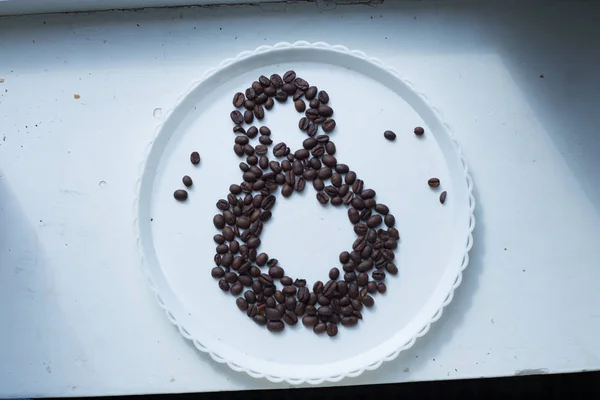 Coffee beans in form of number eight and orchids on white plastic plate. International women's day. 8th march — Stock Photo, Image