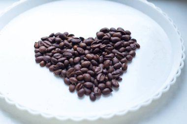 Kahve çekirdekleri güzel arka plan üzerinde kalp şeklinde. Seviyorum. Insparation. Beyaz plaka üzerinde.