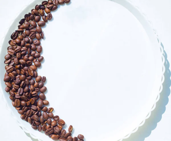 Kaffebönor i månen form på den vita plattan — Stockfoto