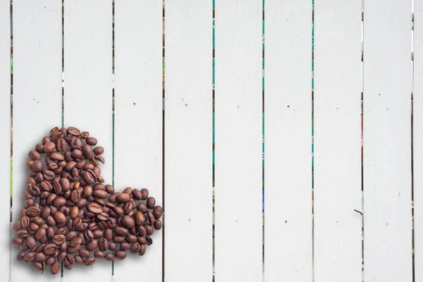 Granos de café en forma de corazón sobre fondo hermoso. Amor. Inscripción. Sobre fondo de madera . — Foto de Stock