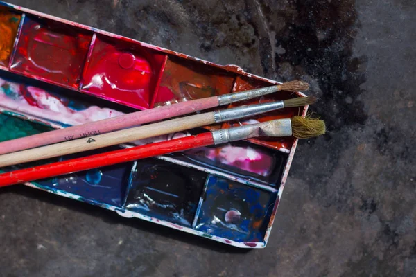 Eski kullanılan suluboya seti ve grunge metal arka plan üzerinde eski fırçalar. Metin için alan