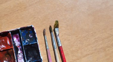 Eski kullanılmış suluboya seti ve ahşap masa üzerinde eski fırçalar. Metin için alan