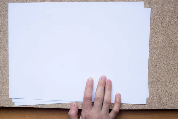 Tangan memegang kertas kosong ukuran a4 untuk kertas surat di latar belakang kayu. Dengan ruang untuk teks — Stok Foto