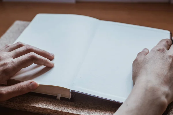 Vrouwelijke handen houden dagboek op het houten bureau. Met ruimte voor tekst — Stockfoto