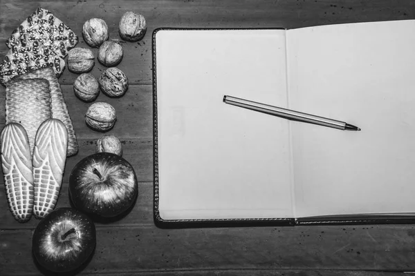Galletas, nueces, manzanas y bloc de notas abierto en el escritorio. Vista superior — Foto de Stock