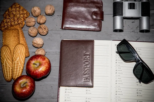 Cookie-kat, dió, alma, pénztárca, távcső, útlevél, napszemüveg és asztalon megnyitott adressbook. Szemközti nézet — Stock Fotó