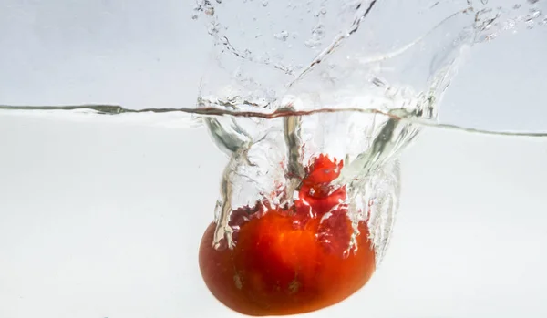 Stříkající rajčata ve vodě — Stock fotografie