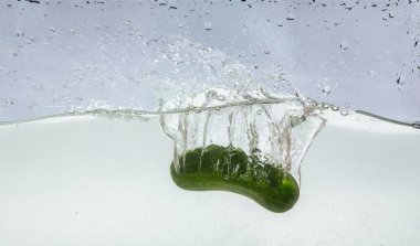 Yeşil salatalık üzerinde beyaz izole suya düştü.