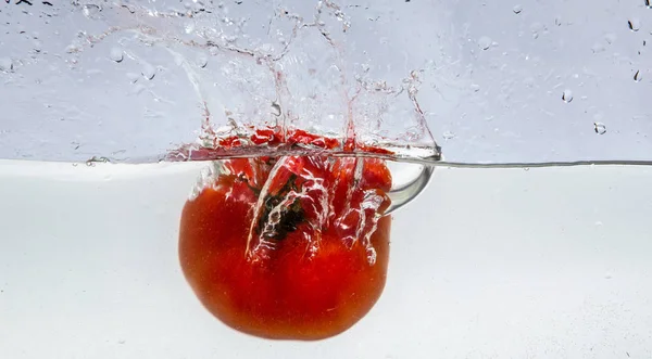 Opspattende tomaten in het water — Stockfoto