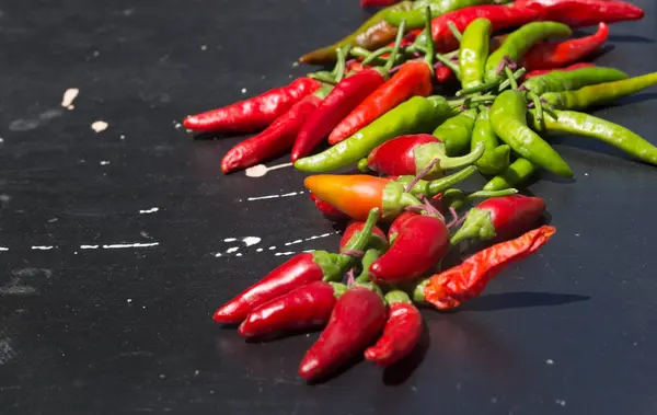 Red hot chili peppers açık havada. Karanlık kurulu arka plan üzerinde kırmızı ve yeşil biber