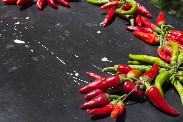 Red hot chili peppers açık havada. Karanlık kurulu arka plan üzerinde kırmızı ve yeşil biber