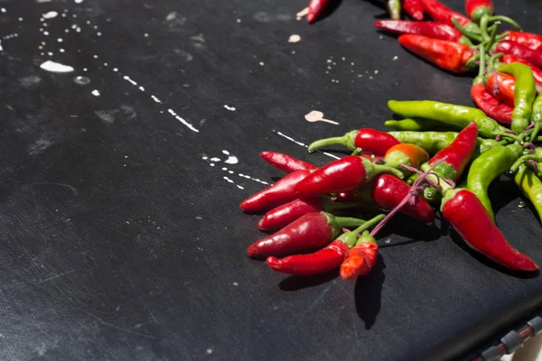 Red hot chili peppers açık havada. Karanlık kurulu arka plan üzerinde kırmızı ve yeşil biber